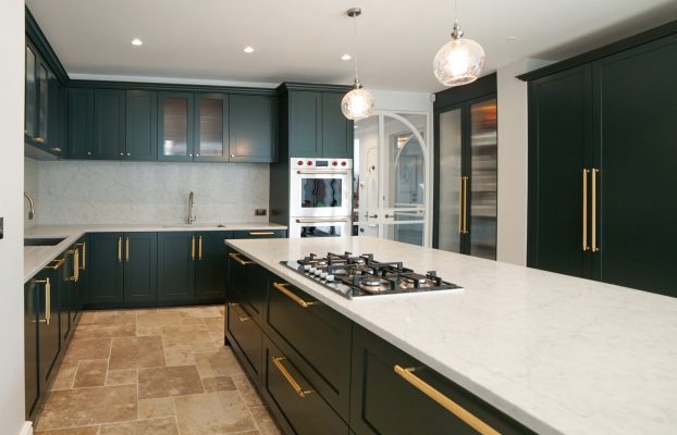 A London kitchen featuring bespoke green cabinets and marble counter tops.