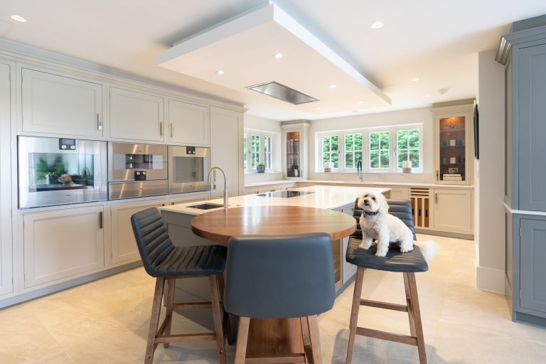A dog sits on a stool in a bespoke kitchen.
