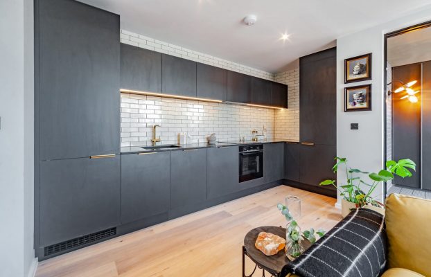 A bespoke kitchen with black cabinets and a yellow couch.