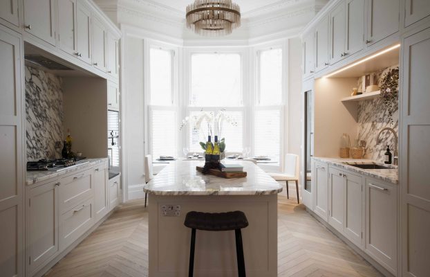 A bespoke white kitchen featuring a marble counter top, designed by London Kitchens and enhanced with Wood Works craftsmanship.