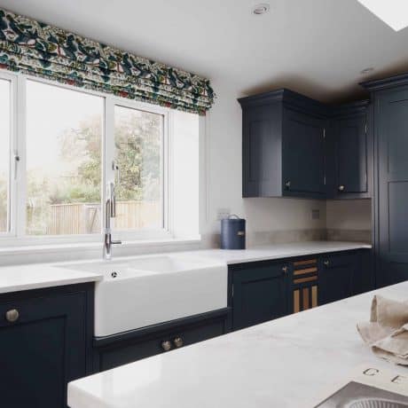 A Wood Works kitchen with blue cabinets and white counter tops offered by London Kitchens.