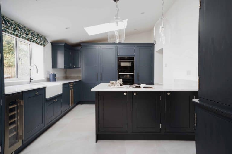A bespoke kitchen in London featuring dark blue cabinets and white countertops.