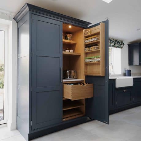 A bespoke blue kitchen with an open door.