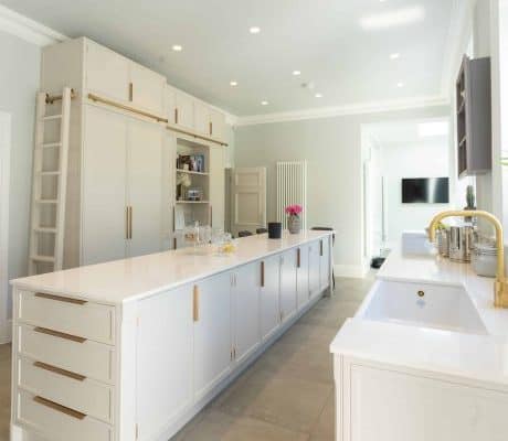 A bespoke kitchen in London with white cabinets and gold hardware.
