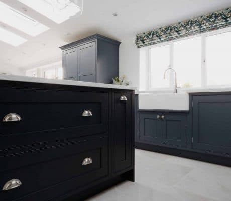 A bespoke kitchen in London featuring dark wood cabinets and white counter tops.