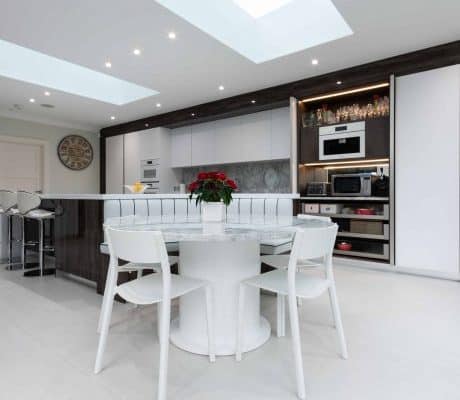 A modern Wood Works kitchen with a white table and chairs.